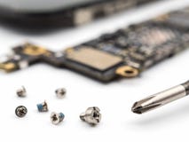 Schraube und Schraubenzieher mit unscharfen Smartphonekomponenten lizenzfreies stockfoto Schraube und Schraubenzieher mit unscharfen Smartphonekomponenten lizenzfreies stockfoto