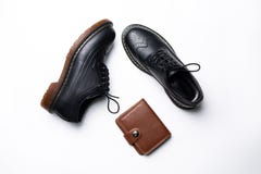 Schwarze lederne Derby-Schuhe mit Polyurethansohlen und ein brauner Geldbeutel mit einem Knopf auf einem wei?en Hintergrund lizenzfreie stockbilder Schwarze lederne Derby-Schuhe mit Polyurethansohlen und ein brauner Geldbeutel mit einem Knopf auf einem wei?en Hintergrund lizenzfreie stockbilder