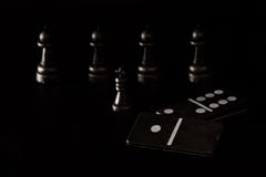 Schwarze Würfeldominos und -Schachfiguren auf einem dunklen Hintergrund stockbild Schwarze Würfeldominos und -Schachfiguren auf einem dunklen Hintergrund stockbild