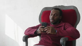 Schwarzer Mann benutzt einen Smartphone, um im Internet in Verbindung zu stehen stock video footage Schwarzer Mann benutzt einen Smartphone, um im Internet in Verbindung zu stehen stock video footage