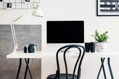 Schwarzer Stuhl durch einen weißen Schreibtisch mit einem Computer und einer Lampe in einem modernen Innenministeriuminnenraum fü stockfoto Schwarzer Stuhl durch einen weißen Schreibtisch mit einem Computer und einer Lampe in einem modernen Innenministeriuminnenraum fü stockfoto