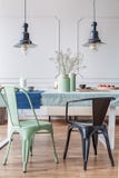 Schwarzer und grüner Stuhl bei Tisch im modernen Esszimmerinnenraum mit Lampen und Blumen Reales Foto lizenzfreie stockfotos Schwarzer und grüner Stuhl bei Tisch im modernen Esszimmerinnenraum mit Lampen und Blumen Reales Foto lizenzfreie stockfotos