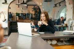 Schöne glückliche Frau, die an Laptop-Computer während der Kaffeepause in der Cafébar arbeitet Stockbild Schöne glückliche Frau, die an Laptop-Computer während der Kaffeepause in der Cafébar arbeitet Stockbild
