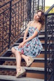 Schöne gut-gepflegte Frau in einem blauen Kleid, das auf der Treppe mit verdrehten Geländern aufwirft lizenzfreies stockbild Schöne gut-gepflegte Frau in einem blauen Kleid, das auf der Treppe mit verdrehten Geländern aufwirft lizenzfreies stockbild
