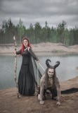 Schöne Hexe mit dem roten Haar und ihrem gehörnten Dämon lizenzfreies stockfoto Schöne Hexe mit dem roten Haar und ihrem gehörnten Dämon lizenzfreies stockfoto