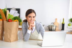 Schöne junge Frau, die Laptop betrachtend kocht stockfoto Schöne junge Frau, die Laptop betrachtend kocht stockfoto
