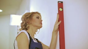 Schöne junge Frau mit messender Wand des Geistniveaus im neuen Haus stock footage Schöne junge Frau mit messender Wand des Geistniveaus im neuen Haus stock footage