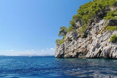 Schöne Klippe im Mittelmeer bedeckt mit grünen Bäumen Hintergrund des blauen Himmels Lizenzfreie Stockfotos Schöne Klippe im Mittelmeer bedeckt mit grünen Bäumen Hintergrund des blauen Himmels Lizenzfreie Stockfotos