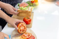 Schöne Mutter hackt Tomate, indem sie Messer auf Schneidebrett verwendet stockbild Schöne Mutter hackt Tomate, indem sie Messer auf Schneidebrett verwendet stockbild
