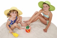 Schöne Schwestern in den Strand-Hüten, die im Sand spielen lizenzfreies stockbild Schöne Schwestern in den Strand-Hüten, die im Sand spielen lizenzfreies stockbild