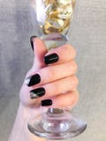Schöne weibliche Hand mit den dünnen Fingern und schwarzer Maniküre mit Gellack mit Silber funkelt auf den Nägeln, die einen Glas lizenzfreie stockbilder Schöne weibliche Hand mit den dünnen Fingern und schwarzer Maniküre mit Gellack mit Silber funkelt auf den Nägeln, die einen Glas lizenzfreie stockbilder