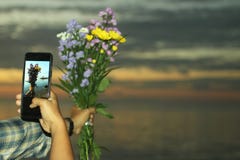Sch?nen Blumenblumenstrau? durch eine andere Hand mit schwarzem intelligentem Telefon in der Hand gefangennehmen, Mehrproze?h?nde lizenzfreie stockfotografie Sch?nen Blumenblumenstrau? durch eine andere Hand mit schwarzem intelligentem Telefon in der Hand gefangennehmen, Mehrproze?h?nde lizenzfreie stockfotografie