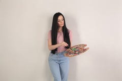 Schöner Brunette mit dem langen Haarlächeln, das eine Farbpalette in ihren Händen hält, steht sie vor einem grauen Hintergrund stockfoto Schöner Brunette mit dem langen Haarlächeln, das eine Farbpalette in ihren Händen hält, steht sie vor einem grauen Hintergrund stockfoto
