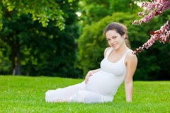 Schöner Park der schwangeren Frau im Frühjahr lizenzfreies stockbild Schöner Park der schwangeren Frau im Frühjahr lizenzfreies stockbild