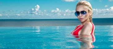 Schönes Blondinemodell mit dem nassen Haar und eleganten dem Make-up, die in einem Pool sitzt stockbild Schönes Blondinemodell mit dem nassen Haar und eleganten dem Make-up, die in einem Pool sitzt stockbild