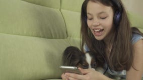 Schönes jugendlich Mädchen in den Kopfhörern Karaokelieder im Smartphone mit Hundevorrat-Gesamtlängenvideo singend stock video Schönes jugendlich Mädchen in den Kopfhörern Karaokelieder im Smartphone mit Hundevorrat-Gesamtlängenvideo singend stock video