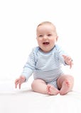 Schönes lachendes glückliches Baby, das auf Bett sitzt Lizenzfreie Stockfotos Schönes lachendes glückliches Baby, das auf Bett sitzt Lizenzfreie Stockfotos