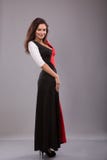 Schönes Mädchen, welches das lange Kleid aufwirft gegen grauen Hintergrund glättet lizenzfreies stockfoto Schönes Mädchen, welches das lange Kleid aufwirft gegen grauen Hintergrund glättet lizenzfreies stockfoto