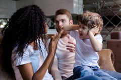 Schönes Paar sitzt auf der Couch mit ihrem kleinen Sohn beim Haben eines Streites lizenzfreie stockfotografie Schönes Paar sitzt auf der Couch mit ihrem kleinen Sohn beim Haben eines Streites lizenzfreie stockfotografie