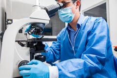 Scientifique masculin regardant des glissières sous le microscope images stock Scientifique masculin regardant des glissières sous le microscope images stock