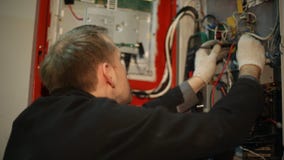 Scientist makes electrical measurements in the switchboard. The scientist makes in the switchboard electrical measurements with a multimeter Scientist makes electrical measurements in the switchboard. The scientist makes in the switchboard electrical measurements with a multimeter
