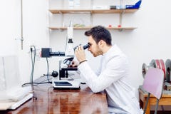 Scienziato con il microscopio, i campioni d'esame e le sonde contaminate in laboratorio speciale fotografia stock libera da diritti Scienziato con il microscopio, i campioni d'esame e le sonde contaminate in laboratorio speciale fotografia stock libera da diritti