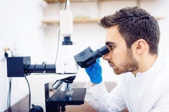 Scienziato medico con il microscopio, i campioni d'esame ed il liquido in laboratorio fotografia stock libera da diritti Scienziato medico con il microscopio, i campioni d'esame ed il liquido in laboratorio fotografia stock libera da diritti