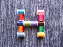 The letter H from the coils of thread on a denim background vector illustration The letter H from the coils of thread on a denim background vector illustration