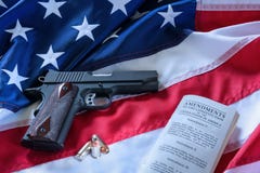 The second amendment and gun control in the US, concept. A handgun, bullets, and the american constitution on the USA flag. stock photo The second amendment and gun control in the US, concept. A handgun, bullets, and the american constitution on the USA flag. stock photo