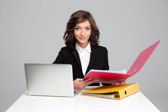 Secretário consideravelmente seguro que trabalha com computador e os dobradores coloridos imagens de stock royalty free Secretário consideravelmente seguro que trabalha com computador e os dobradores coloridos imagens de stock royalty free