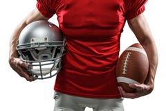 Section médiane de joueur de football américain dans le débardeur rouge tenant le casque et la boule photo libre de droits Section médiane de joueur de football américain dans le débardeur rouge tenant le casque et la boule photo libre de droits