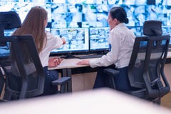 Security guard monitoring modern CCTV cameras in surveillance room. Two Female security guards in surveillance room
