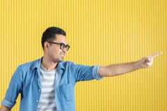 Seiten-Ansicht, Abschluss oben des jungen asiatischen hübschen bärtigen Mannes, tragende Brillen, im Denimhemd, playfully zeigend lizenzfreie stockfotografie Seiten-Ansicht, Abschluss oben des jungen asiatischen hübschen bärtigen Mannes, tragende Brillen, im Denimhemd, playfully zeigend lizenzfreie stockfotografie