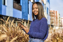 Seitenansicht einer afro-amerikanischen Mädchenstellung, beim Halten der Tablette in ihren Händen und Schauen der Kamera lizenzfreie stockbilder Seitenansicht einer afro-amerikanischen Mädchenstellung, beim Halten der Tablette in ihren Händen und Schauen der Kamera lizenzfreie stockbilder