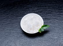 Sel cosmétique marin dans une cuvette blanche avec des feuilles sur un verrat d'ardoise photos stock Sel cosmétique marin dans une cuvette blanche avec des feuilles sur un verrat d'ardoise photos stock