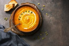 Selbst gemachte K?rbissuppe in einer Lehmplatte gedient mit Sahne, Samen und dunkelbraunem rustikalem Hintergrund des Toasts Drau stockfoto Selbst gemachte K?rbissuppe in einer Lehmplatte gedient mit Sahne, Samen und dunkelbraunem rustikalem Hintergrund des Toasts Drau stockfoto
