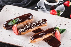 Selbst gemachte Kuchen Eclairs oder profiteroles mit Vanillepudding, Schokolade und Erdbeeren auf dem dunklen Hintergrund gedient stockbilder Selbst gemachte Kuchen Eclairs oder profiteroles mit Vanillepudding, Schokolade und Erdbeeren auf dem dunklen Hintergrund gedient stockbilder