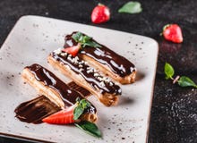 Selbst gemachte Kuchen Eclairs oder profiteroles mit Vanillepudding, Schokolade und Erdbeeren auf dem dunklen Hintergrund gedient stockfotos Selbst gemachte Kuchen Eclairs oder profiteroles mit Vanillepudding, Schokolade und Erdbeeren auf dem dunklen Hintergrund gedient stockfotos
