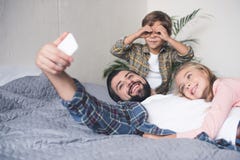 selectieve nadruk van glimlachende vader en jonge geitjes die selfie op smartphone samen nemen stock afbeelding selectieve nadruk van glimlachende vader en jonge geitjes die selfie op smartphone samen nemen stock afbeelding