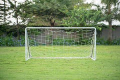 Selective focus on a small soccer goal with rope net puts on the grass field with blurred garden and trees in background royalty free stock photography Selective focus on a small soccer goal with rope net puts on the grass field with blurred garden and trees in background royalty free stock photography