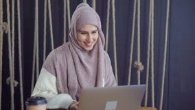 A senhora muçulmana alegre está lendo mensagens no caderno, está sorrindo e está escrevendo a resposta video estoque A senhora muçulmana alegre está lendo mensagens no caderno, está sorrindo e está escrevendo a resposta video estoque