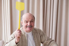 Senior caucasian man holding a fly swatter wanting to kill annoying mosquito