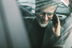 Senior commuter travelling by a taxi and making phone call Royalty Free Stock Photos Senior commuter travelling by a taxi and making phone call Royalty Free Stock Photos