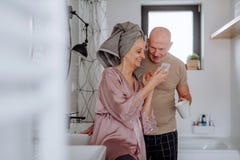 Senior couple in love in bathroom, using smartphone, morning routine concept.