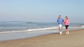 Senior Couple Running On Empty Beach