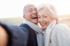 Senior Couple Standing On Beach Taking Selfie stock image Senior Couple Standing On Beach Taking Selfie stock image