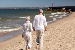 Senior couple walking along summer beach stock photo Senior couple walking along summer beach stock photo