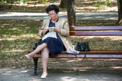 Senior lady sitting on bench in park and knitting tablecloth stock images Senior lady sitting on bench in park and knitting tablecloth stock images