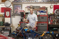Senior man standing behind motorcycle in automobile repair shop Royalty Free Stock Image Senior man standing behind motorcycle in automobile repair shop Royalty Free Stock Image