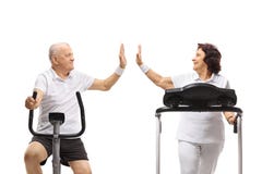 Senior man on a stationary bike and a senior woman on a treadmill high-fiving each other stock photography Senior man on a stationary bike and a senior woman on a treadmill high-fiving each other stock photography